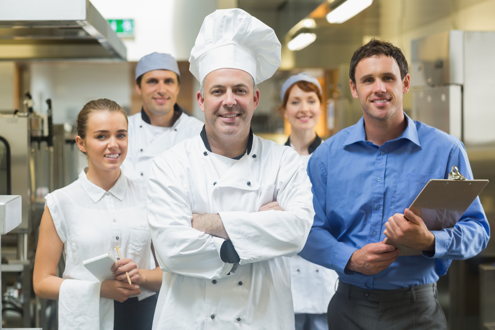 Head chef posing with the team behind him in a profesionnal kitchen