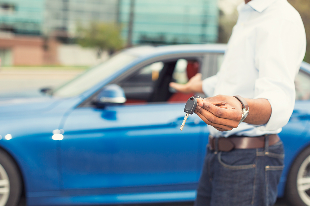 Male hand holding car keys offering new blue car on background-1